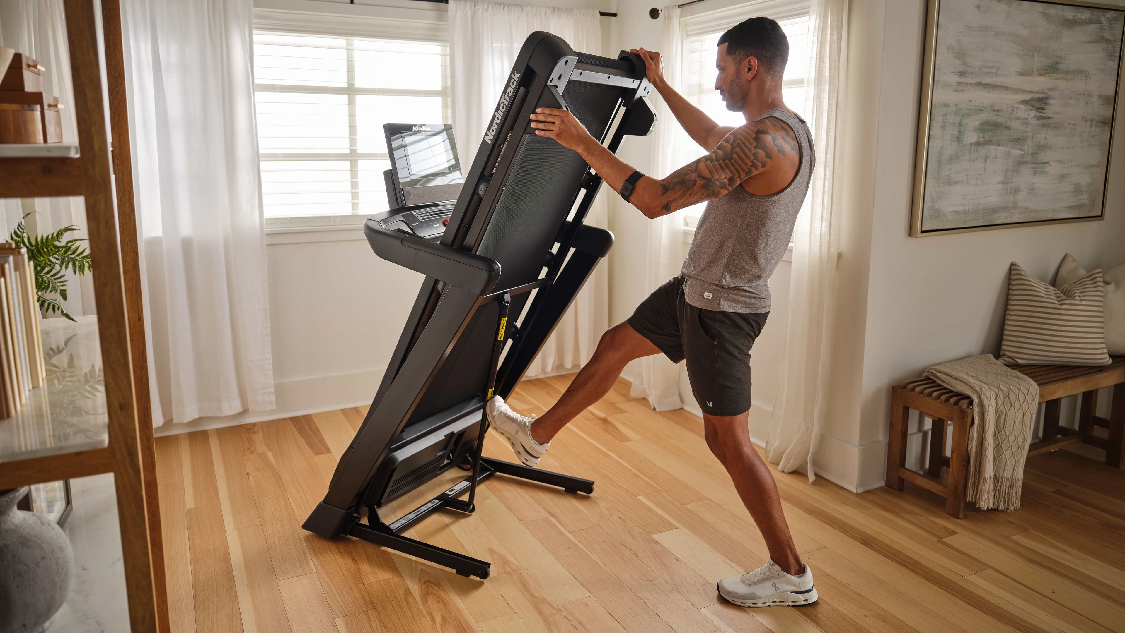 NordicTrack T Series 10 Treadmill folded vertically in a home living space, showing the compact upright storage position ideal for apartments and small floors.