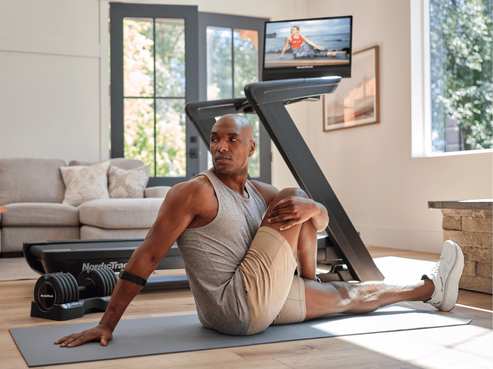 Man doing an off-machine floor stretch using his iFIT screen for guidance