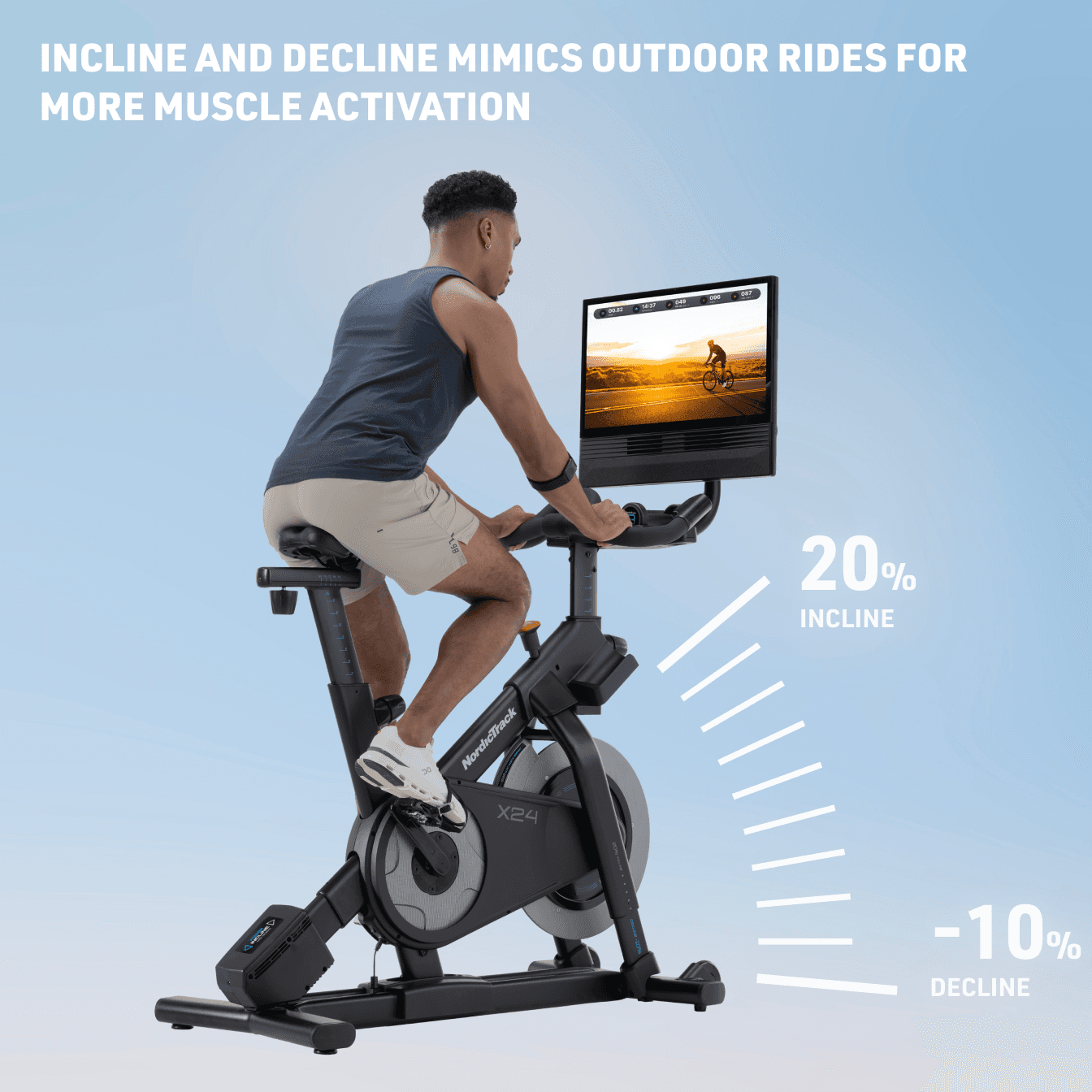 A man in blue tank top and khaki shorts riding the X24 Studio Bike with graphics showcasing its 20% incline to -10% decline.