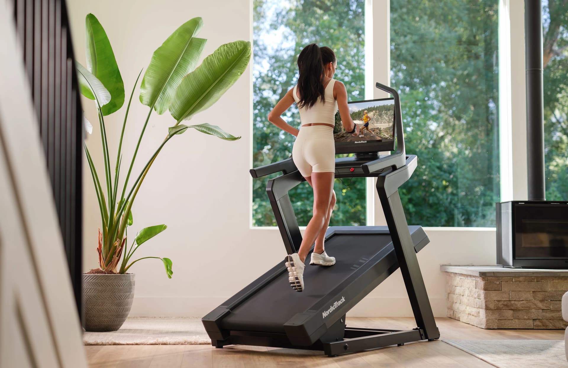 woman using NordicTrack smart treadmill with large screen during guided iFIT workout at home