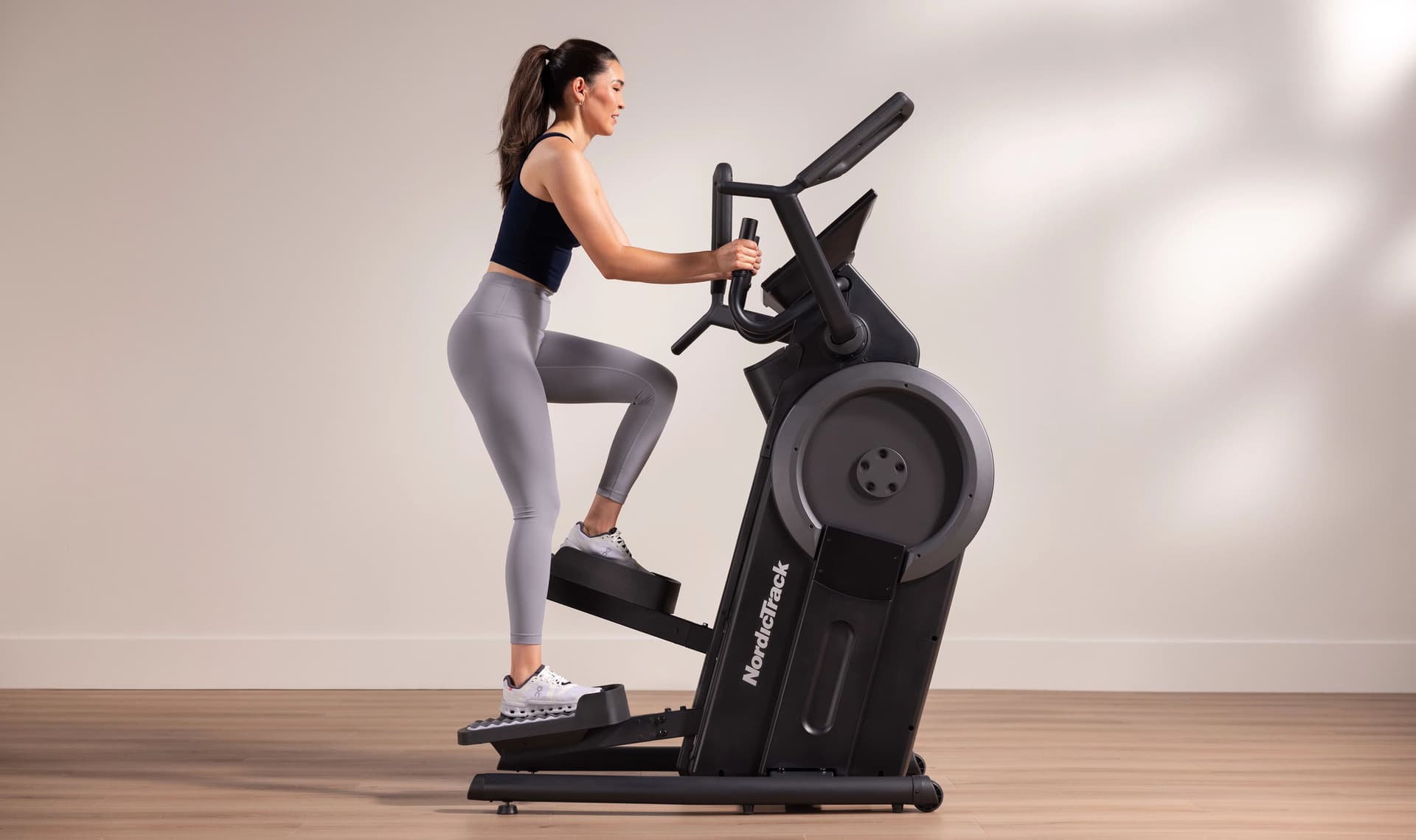 A woman performs a stair-style workout on the NordicTrack Step Climber, highlighting its vertical stepping motion and focused lower-body training design.