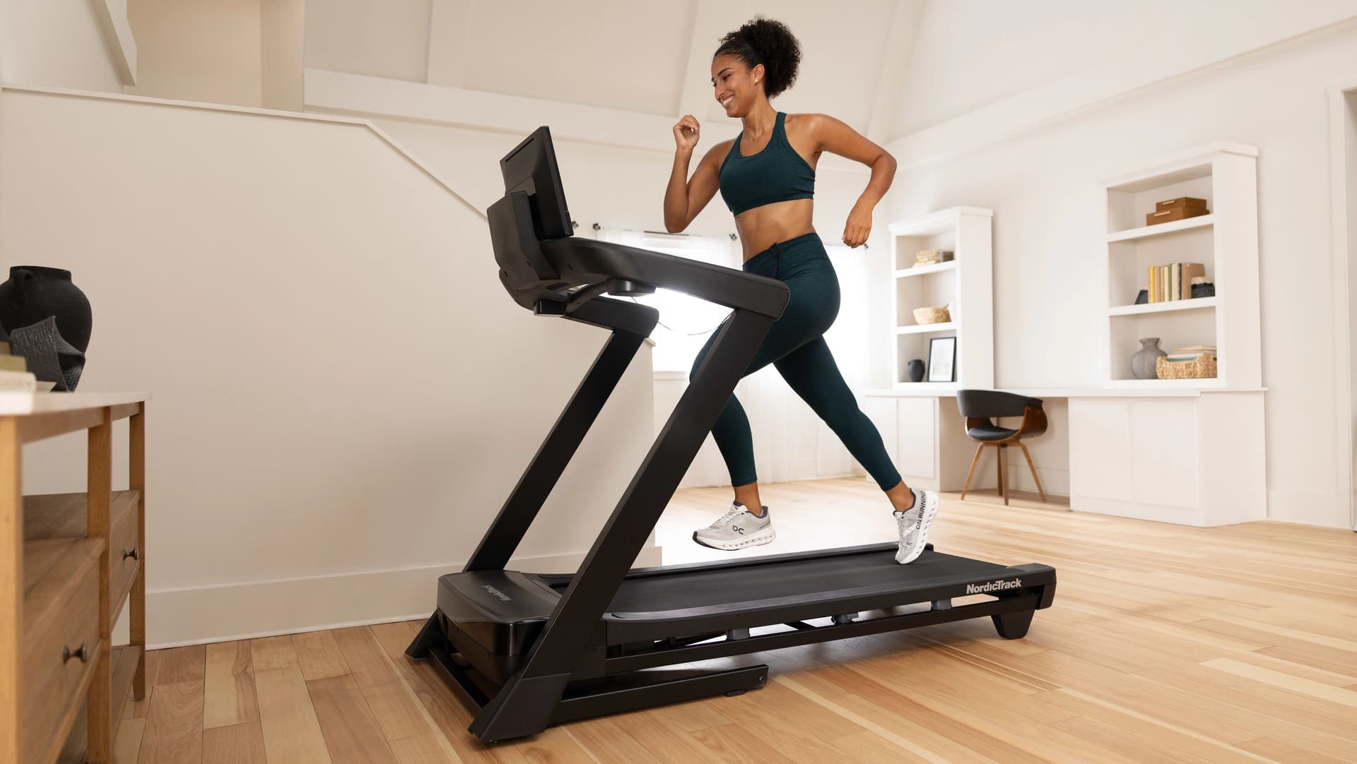 Lifestyle photo showing a user jogging on a NordicTrack treadmill in a bright home gym space, demonstrating everyday cardio workouts supported by connected fitness training.