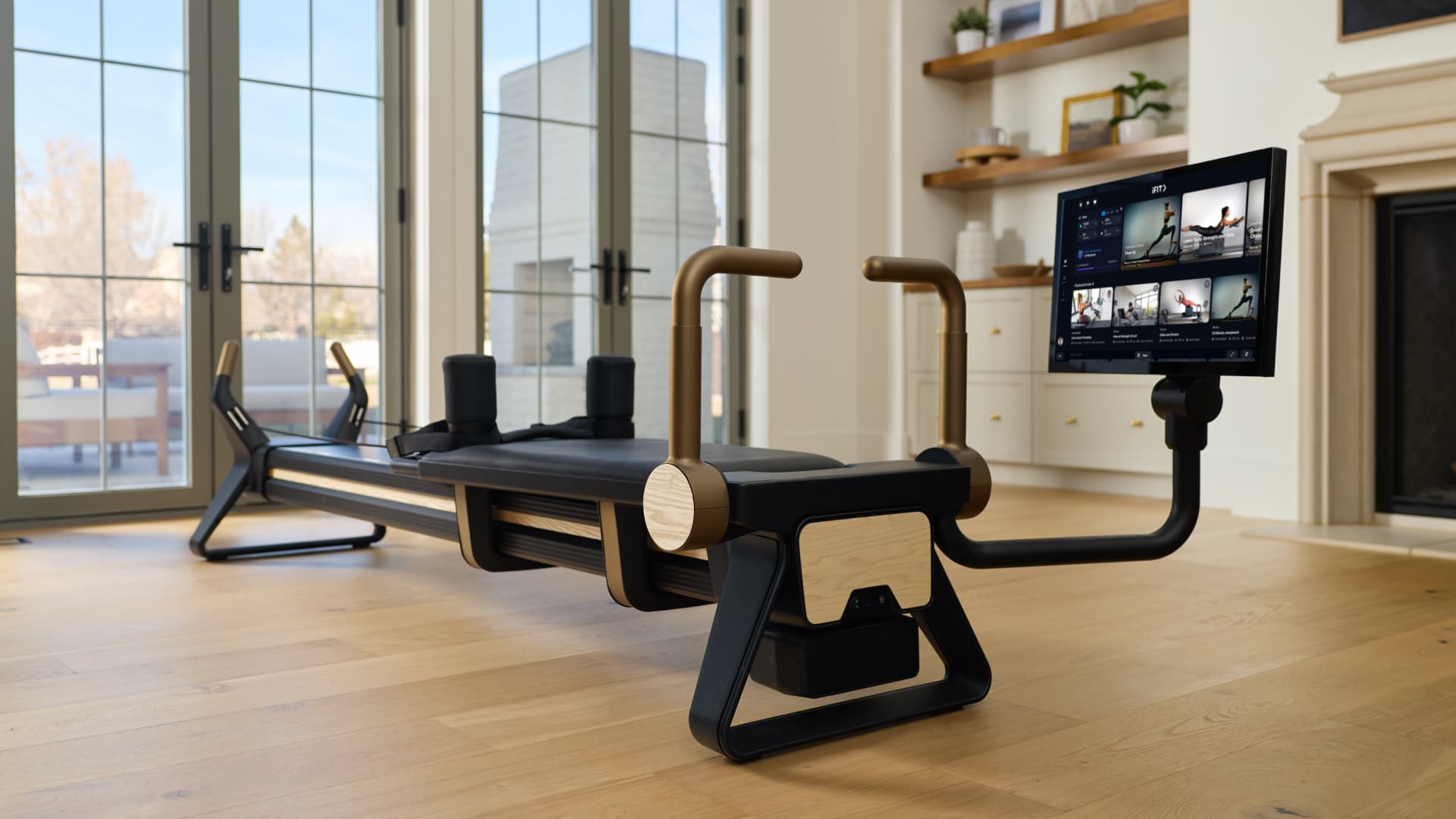 The Ultra 1 Reformer shown in a light-filled home setting with maple finish, compact footprint, and connected iFIT touchscreen interface designed for intentional daily Pilates practice.