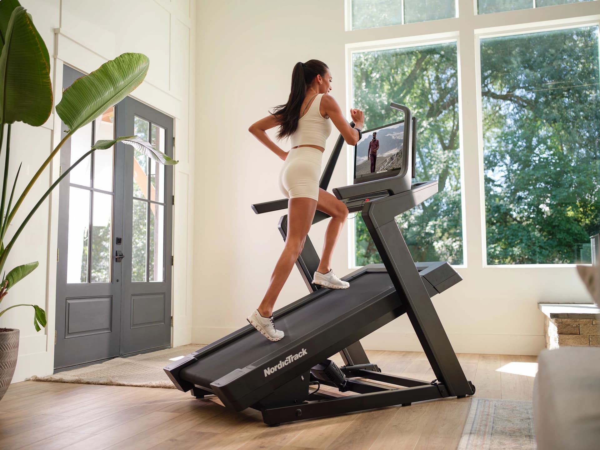 Femme courant sur le tapis de course inclinable NordicTrack X24 pendant une séance d'entraînement à domicile