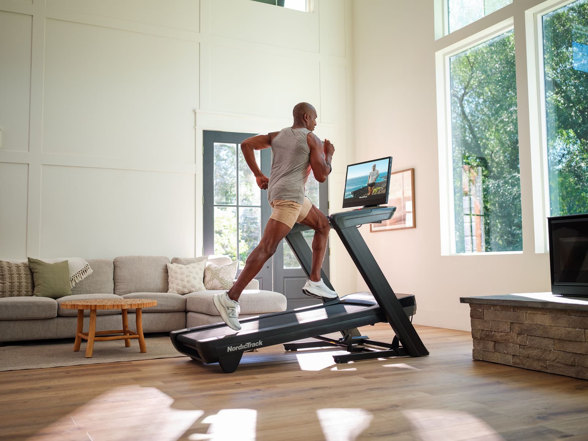 Homme courant sur le tapis de course inclinable et pliable NordicTrack Commercial 2450 pendant une séance d'entraînement à domicile