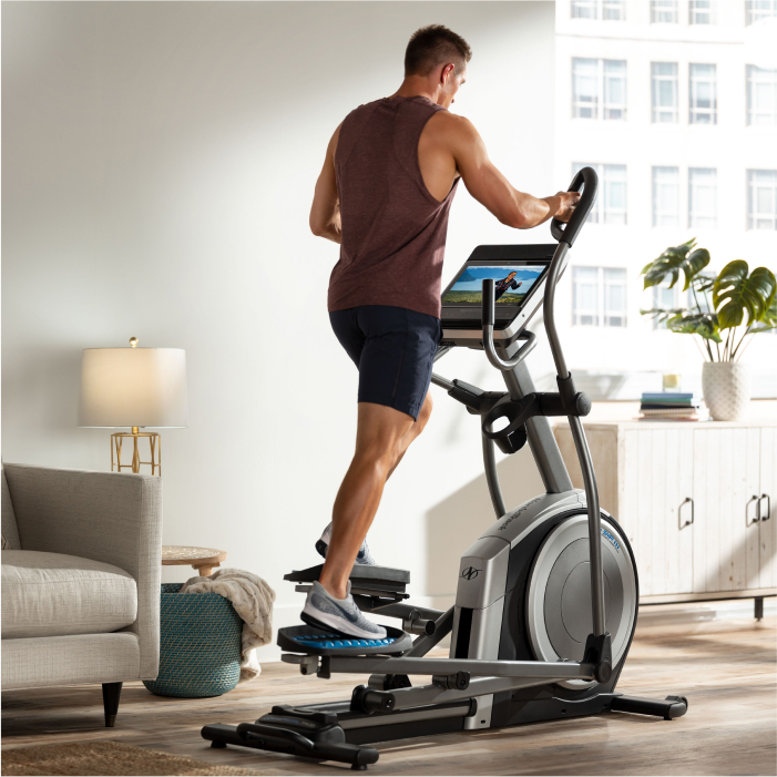 Man Exercising on a NordicTrack Elliptical Using an iFIT Workout That’s Streaming on His Screen