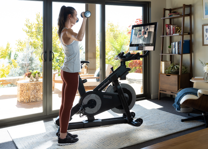 Woman Working Out with iFIT Workout Next to a NordicTrack Exercise Bike