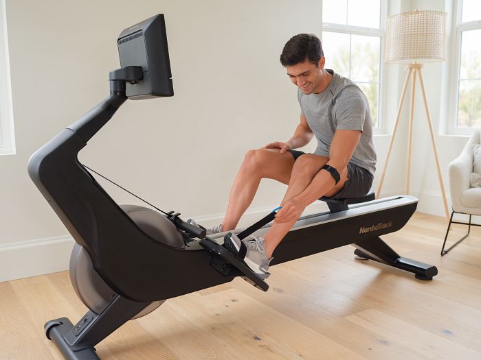 Man Adjusting the Pedal Straps on His NordicTrack Rowing Machine